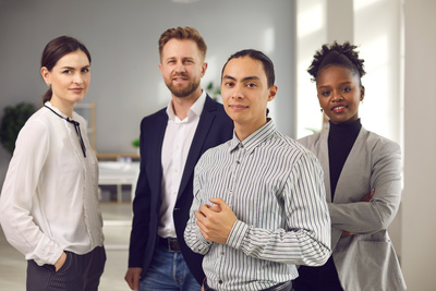 Quatre professionnels posent ensemble dans un bureau.